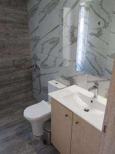 a bathroom with a white toilet and a sink at blue view sea apartment in Ratzaklíon