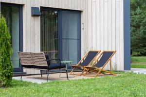 zwei Stühle und ein Tisch vor einem Gebäude in der Unterkunft Albatross RELAX seaside design apartment with terrace in Ķesterciems