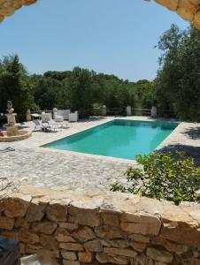 een zwembad met een stenen muur eromheen bij Trullo Nicola in Ceglie Messapica