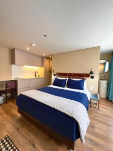 a bedroom with a large blue bed and a kitchen at Grace Chapinero in Bogotá