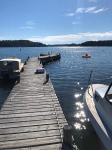 a dock on a lake with boats in the water at Semesterhus i Stockholms skärgård, Runmarö. in Nämdö