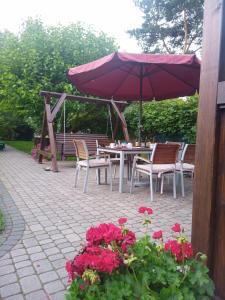 a table and chairs with an umbrella and flowers at Pokoje Sobie na Wyspie in Gdańsk