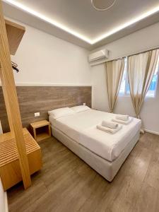 a bedroom with a large white bed and two windows at Hotel Aulona in Sarandë