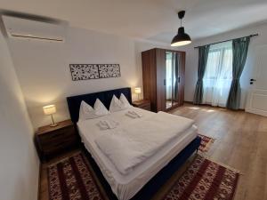 1 dormitorio con 1 cama grande con sábanas blancas en Maximus Apartments en Sighişoara