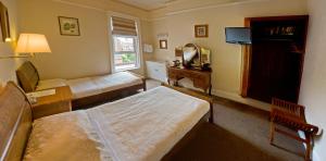 a hotel room with two beds and a television at Somerton House Rooms Only in Belfast