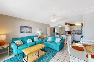 a living room with blue couches and a kitchen at Summit 723 in Panama City Beach