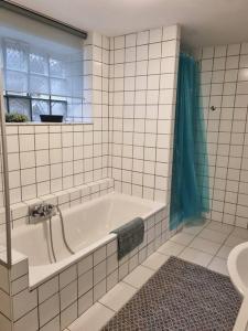 a white tiled bathroom with a tub and a window at Gemütliche Oase - Geräumige Unterkunft in Sarreguemines