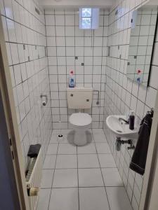 a white tiled bathroom with a toilet and a sink at Gemütliche Oase - Geräumige Unterkunft in Sarreguemines