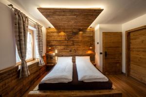 two beds in a room with a wooden wall at Ciasa Marizana in Soraga