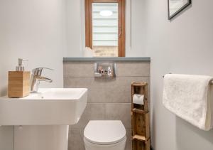 ein Badezimmer mit einem weißen Waschbecken und einem WC in der Unterkunft Midsomer House in Aldeburgh