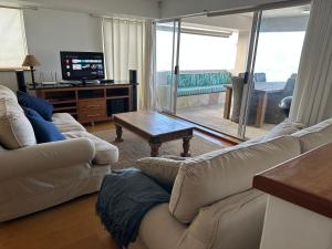 un soggiorno con divano, tavolo e TV di Beach Vibes Clifton! a Città del Capo