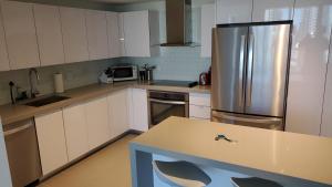 a kitchen with white cabinets and a stainless steel refrigerator at Canvas Condo in Miami