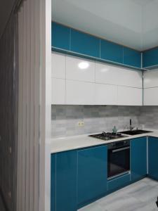 a kitchen with blue and white cabinets and a stove at Family apartament in Batumi