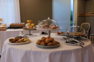 een tafel met borden met gebak en dienbladen met eten bij Lake Hotel La Pieve in Pisogne