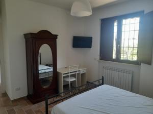 1 dormitorio con espejo, cama y escritorio en Serroni Alto, en Battipaglia