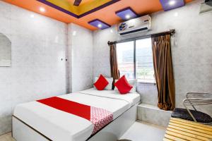 GauripurにあるOYO Flagship The Restの赤い枕と窓付きのベッドが備わる客室です。
