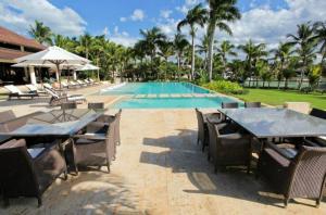 uma piscina com mesas e cadeiras ao lado de um resort em Sunny Vacation Villa No 43 em San Rafael del Yuma