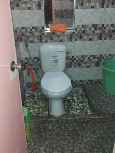 a bathroom with a toilet in a tiled room at Budhis Home in Bromo