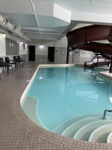 a large swimming pool in a room with tables and chairs at Ramada by Wyndham Airdrie Hotel & Suites in Airdrie