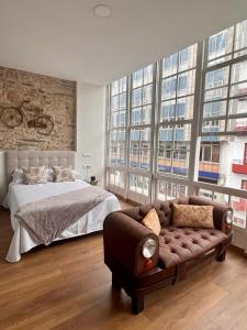 1 dormitorio con cama, sofá y ventanas en Hostal Zahara, en Ferrol