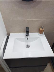 a white bathroom sink with a soap dispenser on it at Le triplex Côté plage plein Sud in Courseulles-sur-Mer