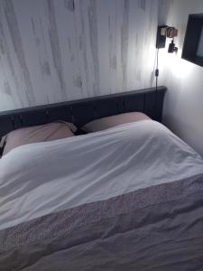 Una cama con sábanas blancas y almohadas en un dormitorio en Le triplex Côté plage plein Sud, en Courseulles-sur-Mer