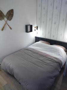 a bed in a bedroom with a fan on the wall at Le triplex Côté plage plein Sud in Courseulles-sur-Mer