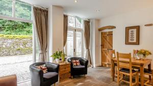 a living room with a desk and chairs and a table and windows at Kestrel Cottage in Chinley