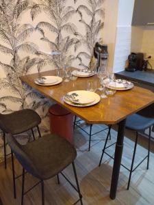 a wooden table with chairs and plates and wine glasses at Le triplex Côté plage plein Sud in Courseulles-sur-Mer
