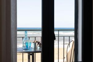 a table with a bottle on a balcony with the beach at Tusa Bay in Castel di Tusa