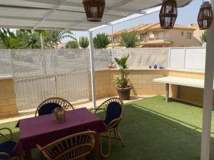 um pátio com uma mesa e cadeiras e uma mesa com uma toalha de mesa roxa em Bungalow planta baja con amplia terraza 120m2 residencial privado con piscina em Pilar de la Horadada