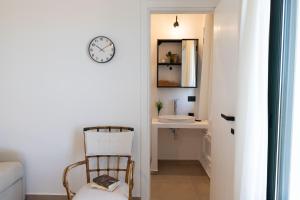 a bathroom with a clock on the wall and a chair at Tusa Bay in Castel di Tusa