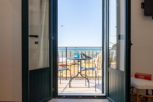 a door leading to a balcony with a table and the ocean at Tusa Bay in Castel di Tusa