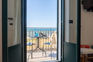 a room with a balcony with a table and the ocean at Tusa Bay in Castel di Tusa