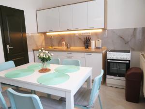 a kitchen with a white table and blue chairs at Hegyköz Vendégház in Pusztafalu