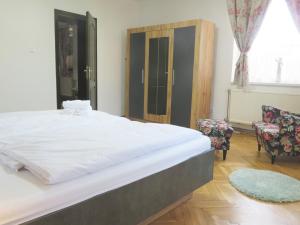 um quarto com uma grande cama branca e 2 cadeiras em Hegyköz Vendégház 
