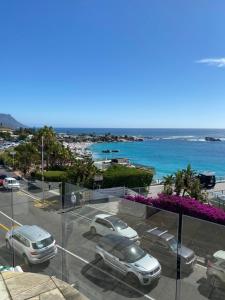 a view of a parking lot with cars and the ocean at Beach Vibes Clifton! in Cape Town