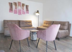 a living room with two pink chairs and a couch at Hegyköz Vendégház 