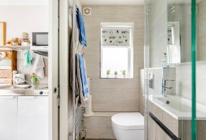 a bathroom with a toilet and a sink and a window at Arlington - private room and en-suite in Woking