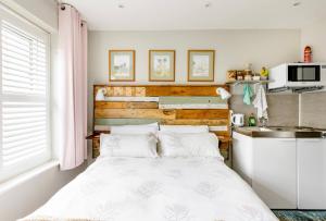 ein kleines Schlafzimmer mit einem Bett und einer Küche in der Unterkunft Arlington - private room and en-suite in Woking