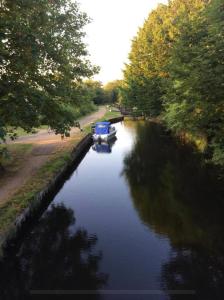 ein Boot auf einem Fluss mit Bäumen und einer Straße in der Unterkunft Arlington - private room and en-suite in Woking