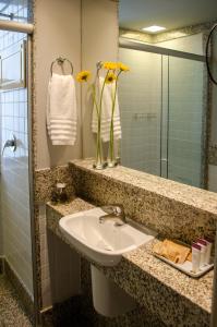 a bathroom with a sink and a vase with yellow flowers at Royal Boutique Savassi Hotel in Belo Horizonte