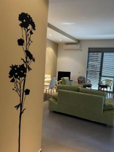uma sala de estar com um sofá verde e flores na parede em M&R Boutique Apartment in Orikum em Orikum