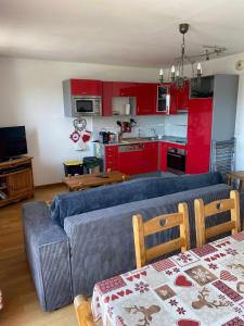 a living room with a couch and a kitchen with red cabinets at Appartement tout confort - Belle vue sur le Cambre d'Aze in Bolquere Pyrenees 2000