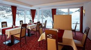 a dining room with tables and chairs and snow at Apart Garni Jungmann in Ischgl