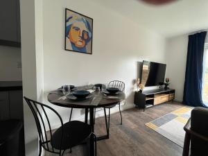 a dining room with a table and chairs and a tv at KENT, DARTFORD STATION APARTMENTs in Dartford