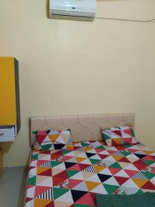 a bed with a colorful quilt and pillows on it at Shubham guest house in Muzaffarpur