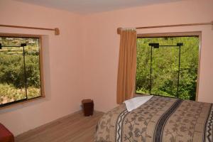 a bedroom with a bed and two windows at Allpa Tika Lodge in Amantani