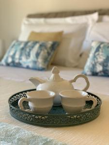 a tea set on a tray with two cups on a bed at Le Cupole di Palermo in Palermo
