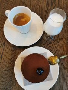 two plates with a chocolate dessert and a glass of milk at Albatross RELAX seaside design apartment with terrace in Ķesterciems
